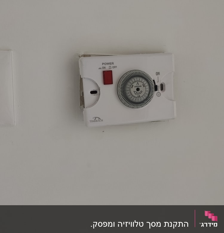 טיימר חשמלי עם כפתור הפעלה על קיר